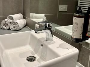 a bathroom sink with a faucet and some towels at Apartimo München-Unterhaching in Unterhaching +17 photos