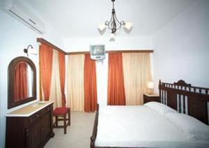 ein Schlafzimmer mit einem Bett, einer Kommode und einem Spiegel in der Unterkunft Kelenis Apartments in Karterados