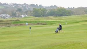 a man with a golf cart on a golf course at 102, Duckpool Lodge in Bude