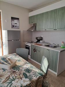 a kitchen with green cabinets and a table and a sink at Megi Apartments, Nesebar sity in Nesebar