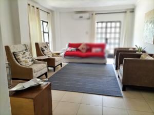 uma sala de estar com um sofá vermelho e cadeiras em Sunbirds Chobe Hotel em Kasane