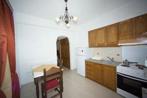 eine Küche mit Holzschränken und einem Tisch und einem Kronleuchter in der Unterkunft Kelenis Apartments in Karterados