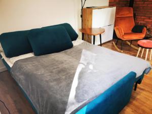 uma cama com um cobertor azul e cinzento e uma cadeira em Apartament Chełmsko Śląskie em Chełmsko Śląskie