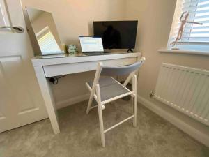 escritorio con ordenador portátil y silla en la habitación en 3 bedroom house - Hampton Water, en Peterborough