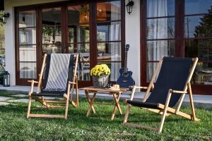 2 chaises, une table et une guitare sur la pelouse dans l'établissement Top - kuća za odmor, à Bukovik