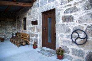 un edificio de piedra con una puerta de madera y un banco en A CASA DA MOREIRA - Casa rural en Ponte Maceira, en A Coruña
