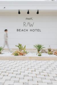 a man walking past a beach hotel sign at RAW BEACH HOTEL in Antalya