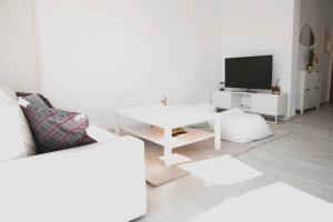 a white living room with a white table and a tv at Lovely Modern 1 BR apartment in Luxembourg