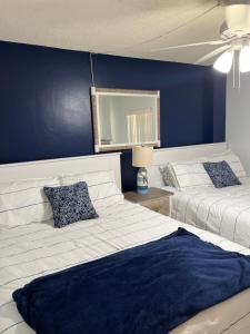 a bedroom with two beds and a blue wall at Ponce de Leon Towers in New Smyrna Beach