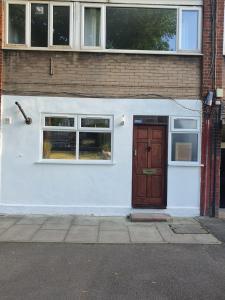 een wit gebouw met een bruine deur en ramen bij Limehouse Guest House Central East London in Londen