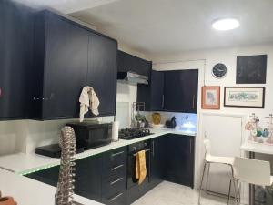een keuken met zwarte kasten en een fornuis met oven bij Limehouse Guest House Central East London in Londen