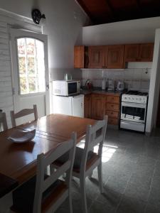 Una cocina con una mesa de madera y una mesa y sillas. en Los Choiques Madryn, en Puerto Madryn