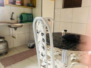 una cocina con una mesa con una silla en blanco y negro en Kitnet para 5 pessoas com cozinha perto do aeroporto en Natal