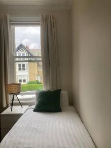 a bed with a green pillow in front of a window at Spacious & Bright 3 bed Harrogate Apartment in Harrogate