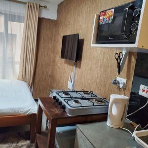 a room with a stove and a tv on the wall at Lovely & Cozy Compact Studio Near Airport with Rooftop View in Nairobi