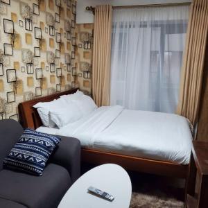 a bedroom with a bed and a window and a couch at Lovely & Cozy Compact Studio Near Airport with Rooftop View in Nairobi
