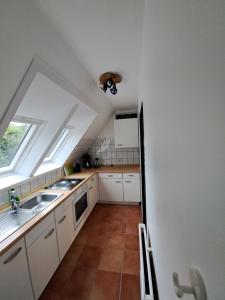 a kitchen with white cabinets and a sink and a window at Nei Stich 19a Wohnung 1 in Norddorf +4 photos