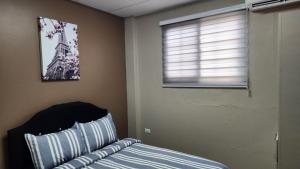 1 dormitorio con 1 cama y una ventana con una foto en The Layover - 6 mins from the airport, Fully equipped for short and long stays en Kelly Village