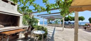 un patio con mesa, sillas y el océano en Apartman Figaro sa dva kupatila uz more i plažu s pogledom na Split, en Kaštela