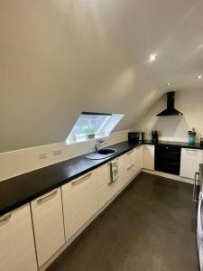 a kitchen with white cabinets and a black counter top at BS - Luxury 4 bed apartment with garage in town centre in Stratford-upon-Avon