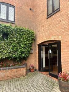 a brick building with an open door with flowers at BS - Luxury 4 bed apartment with garage in town centre in Stratford-upon-Avon