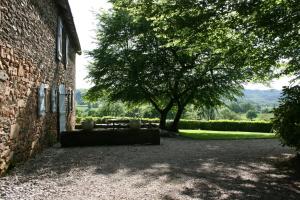 a tree sitting next to a brick building with a table at La Bergerie in Beaulieu-sur-Dordogne