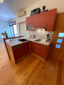 a kitchen with red cabinets and a wooden floor at Apartmán u Dómu in Olomouc
