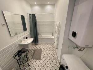La salle de bains blanche est pourvue d'un lavabo et d'une baignoire. dans l'établissement CITY CENTER 1, cozy 2br in the city center!, à Budapest