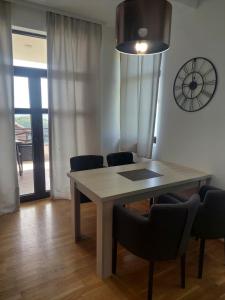 a dining room table with chairs and a clock on the wall at Apartmansko naselje DVORI in Kopaonik