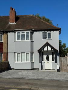 une maison blanche avec une porte blanche et un portail dans l'établissement 3 Bedroom House with Garden in London, à Cheam