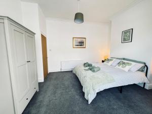 ein weißes Schlafzimmer mit einem Bett und einem Schrank in der Unterkunft Rockcliffe Retreat, Stylish Coastal Apartment in Whitley Bay