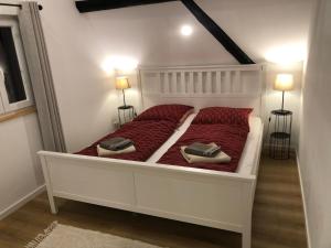 a white bed with red sheets and two pillows on it at Ferienhaus im Städtle in Müllheim