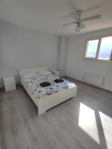 a white bedroom with a bed and a ceiling fan at La perle de Sète Maison bord de l étang Animaux bienvenus Sur demande in Sète