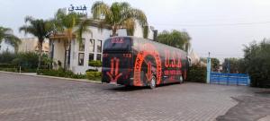 un autobús rojo estacionado frente a un edificio en HOTEL OUM EL FADL, en Fkih Ben Salah