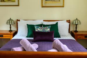 a bed with purple blankets and pillows on it at The Farthings Cotswolds Holiday Cottage in Chipping Campden
