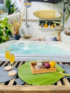 een dienblad met fruit en drankjes op een tafel naast een zwembad bij Évasion Tropicale - Villa d'Artiste avec Jacuzzi Privé dans un jardin Exotique in Mérignac