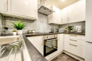 Two Bed Stylish Apartment in Heart of West End في غلاسكو: مطبخ مع دواليب بيضاء ومغسلة