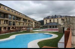a resort with a swimming pool in front of some buildings at PLAYASDEBARREIROs in San Miguel de Reinante