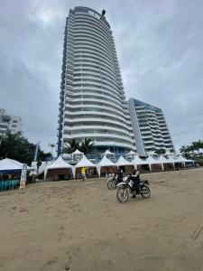 a person riding a motorcycle on the beach with a building at Grand Diamond Beach (TONSUPA) in Tonsupa