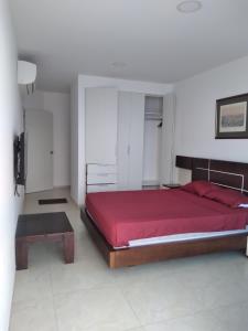een slaapkamer met een groot rood bed en een tafel bij Grand Diamond Beach (TONSUPA) in Tonsupa