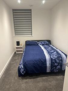 a bedroom with a bed with a blue comforter and a window at Flat beckenham road in Beckenham