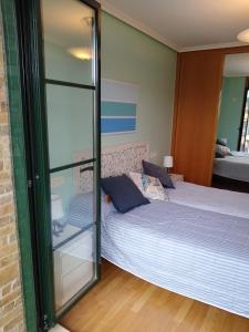 a bedroom with a bed and a glass wall at PLAYASDEBARREIROs in San Miguel de Reinante +22 photos