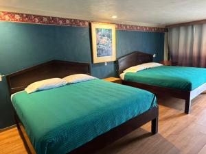 2 camas en un dormitorio con paredes azules en Provo Inn & Suites, en Provo