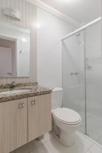 a bathroom with a toilet and a glass shower at Conforto Tranquilidade apto c garagem in Curitiba
