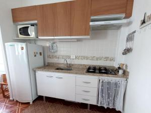 uma cozinha com um frigorífico branco e um lavatório em Solar Canto do Forte na Praia Grande