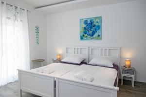 a white bedroom with a large white bed with two pillows at Vila Lavanda in Bribir