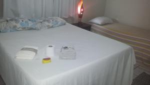 a bed with a white sheet and two beds with towels at Pousada Hostel Villa Bella Mar in Natal