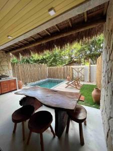 a table and stools in a patio with a pool at Villa Jucá Casa 03 in Pôrto de Pedras