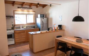 a kitchen with a table and a refrigerator at Casa en La Cascada in San Martín de los Andes