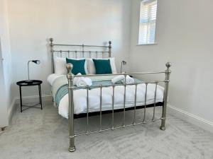 Un dormitorio con una cama de metal con almohadas azules y blancas en The Town House, whole house suitable for contractors and families, en Market Harborough